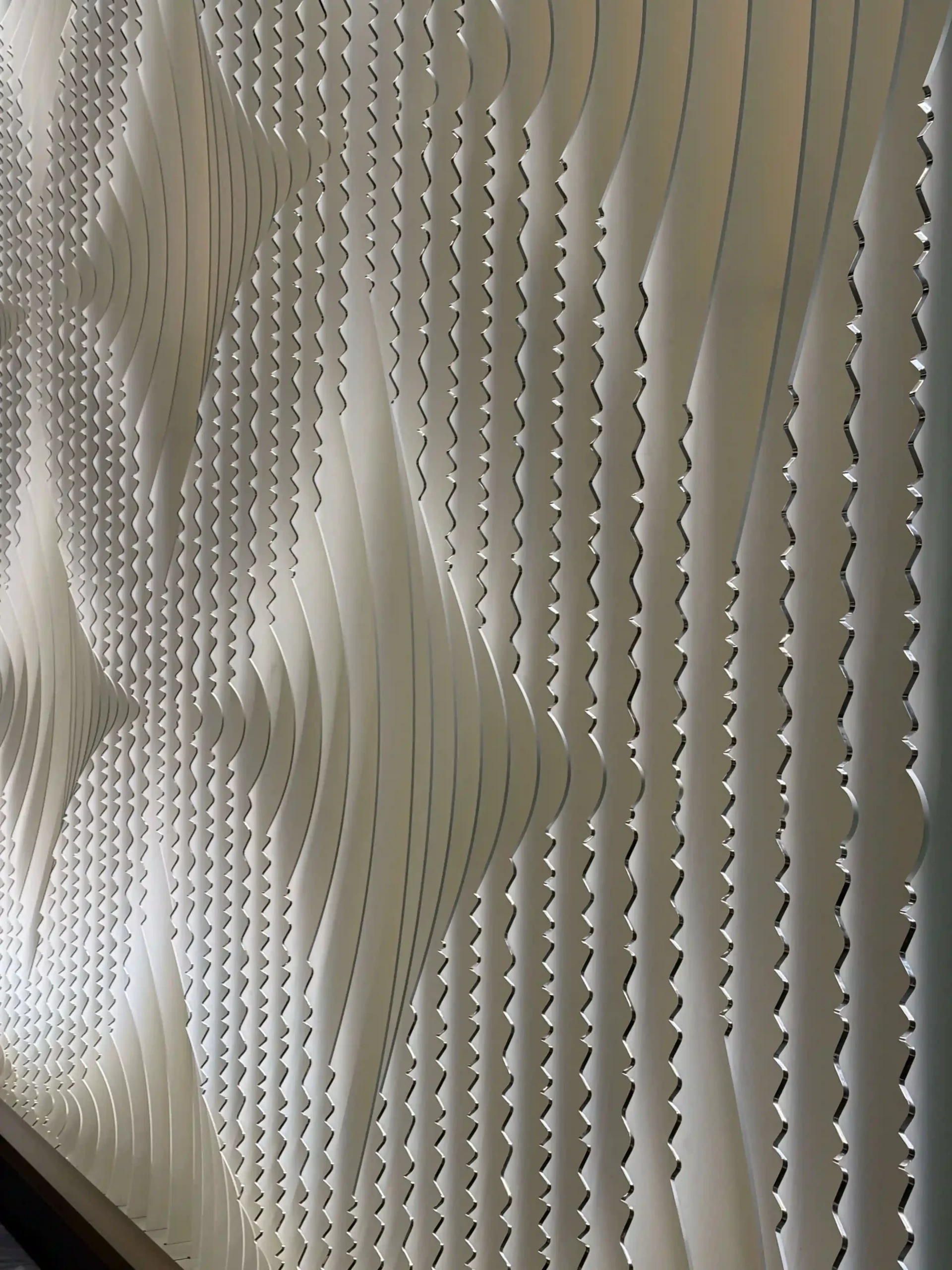 Close-up of textured white wall art with wavy patterns.